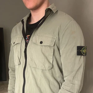 Stone Island Overshirt - Tja, säljer min feta stilrena Stone Island overshirt nu. Den är tunn och är perfekt att ha till sommaren och om du ska ha den på våren/hösten så är det bara att ta på sig en tröja under så är det löst. Inga defekter alls