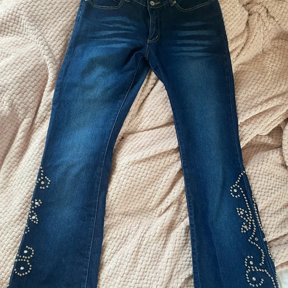 Lågmidjade bootcut jeans med coola detaljer på benen (en ”pärla” borta på höger ben)! 39 cm bredd, 102 cm full längd,  79 cm innerbenslängd. Säljer då de är för stora (jag är 166 cm). Skriv gärna i DM vid frågor 💗. Jeans & Byxor.