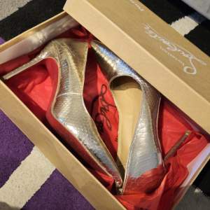 One of Christian Louboutin's most iconic creations, the Kate pumps are designed to enhance the foot's sensual arch. The metallic uppers are crafted  from grained leather and shaped to a  pointed-toe silhouette, balanced on a stiletto heel.  