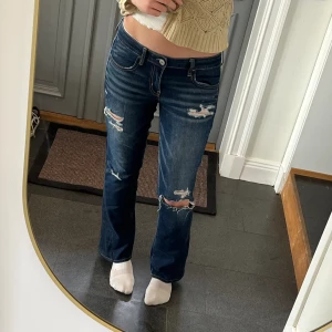 Lågmidjade bootcut jeans från American Eagle  - Lågmidjade mörkblå jeans från American Eagle som jag har sytt till bootcut. Står storlek 8 och passar mig som är 172 och brukar ha S eller M, förutom att de är lite korta på mig. Tvärs över midjan är det 39 cm + stretch och innerbenslängden är 75 cm.
