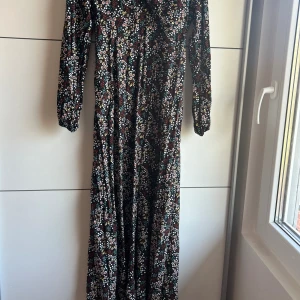Lång klänning  - En lång blommig klänning som är v-ringad. Knappt använd och är i ganska bra skick. Storlek S