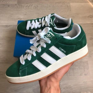 Adidas campus 00s - Säljer ett par helt nya & oanvända adidas campus 00s i färgen grön & storlek 38. Skorna är slutsålda både i butik och på nätet. Vita och gröna skosnören ingår, kvitto finns! 