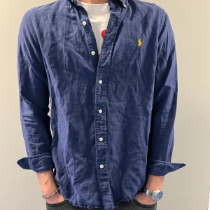 Ralph lauren skjorta - Fräsh och stirlig linne skjorta till sommaren i storlek M. Sitter perfekt på mig som är 185cm. Inga defekter på skjortan alltså i väldigt fint skick. Skriv gärna vid funderingar