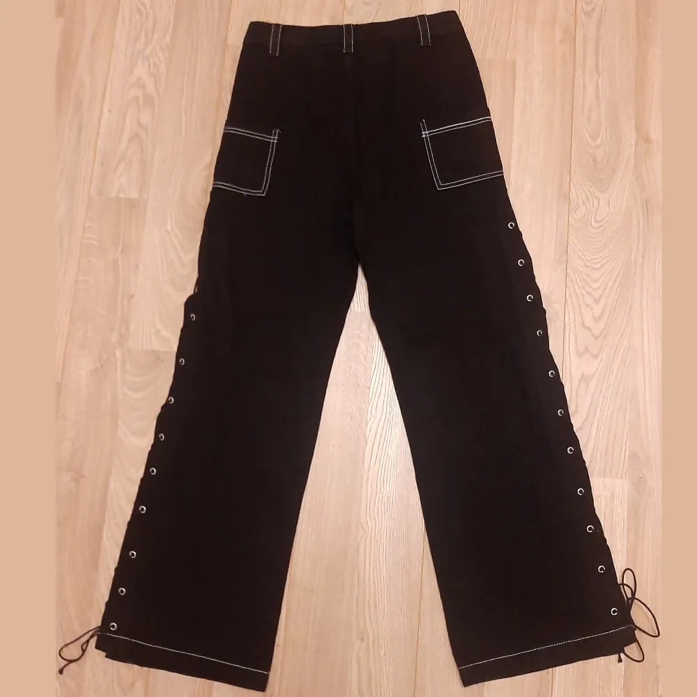 Svarta, vida baggy jeans med öppna sömmar längs benen och vit kontrastsöm. Gothstil. Varken testade eller använda. (Köpt fel storlek). Strlk: M.. Jeans & Byxor.
