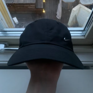 Nike Keps - Svart Nike keps med silver Nike ”swoosh” relativt bra skick (kan tvättas innan fraktning vid önskan) kom privat för fler frågor!//william