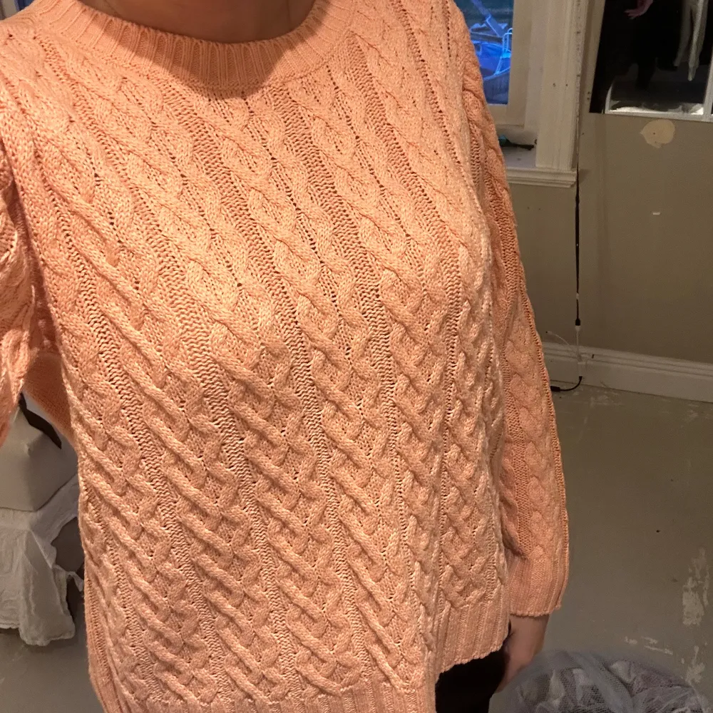 Kabelstickad tröja som är i korall/ rosa/orange färg. Ifrån vila. Väldigt fin och fin att ha under sommarkvällar eller nu. Storleken är L men den passar mig som är en S så skulle säga att den passar både M/S. Stickat.