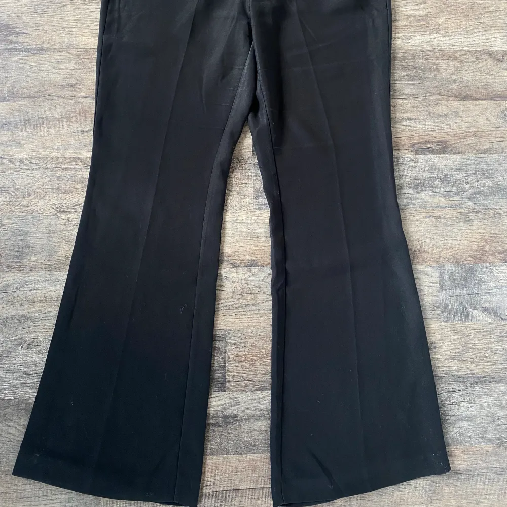 Svarta kostymbyxor från NLY TREND (Nelly.com) med utsvängda ben, försluts med en knapp och dragkedja. Två fickor framtill samt två fickor som detalj baktill.. Jeans & Byxor.