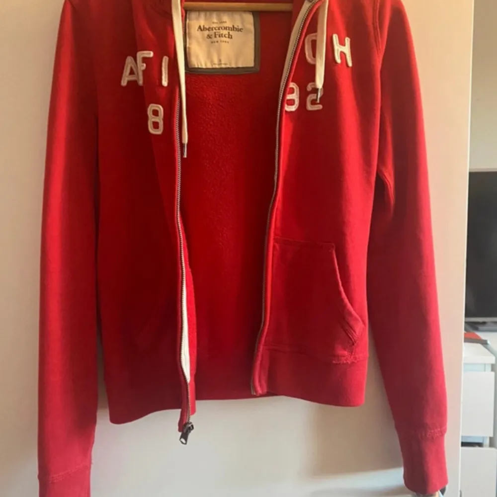 Superfin röd hoodie från Abercrombie & Fitch! Small Huva med grått foder  Fickor fram  Dragkedja  Snören  Allt toppenbra! . Hoodies.