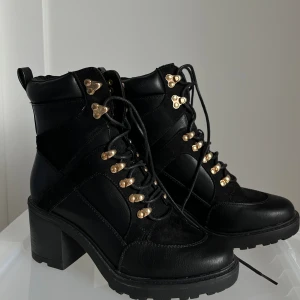 Ankle boots med klack - Svart ankle boots med klack. Knytsnören på framsidan med guld detaljer. Nyskick endast använt 1 gång