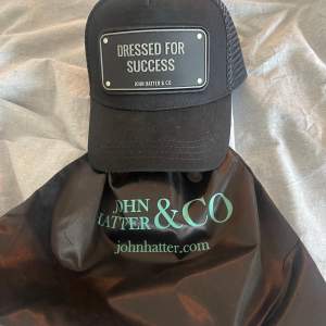 En svart John Hatter Rubber Cap ”Dressed for Success (plattan med text är i plast). Kepsen är inte använd och kepspåsen följer med i köpet. Nypris 500 men säljer för 250🤝