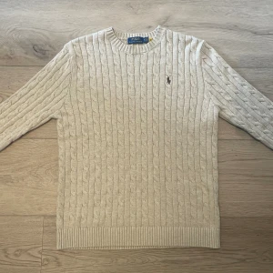 RALPH LAUREN KABELSTIKAD - Säljer denna stilrena och snygga kabelstickade tröjan i beige färg ifrån Ralph Lauren, eftersom inte passade riktigt.