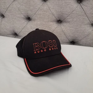 Hugo Boss keps - Hugo Boss keps svart med röda detaljer, Hugo Boss finns ej kvar och säljs ej längre.