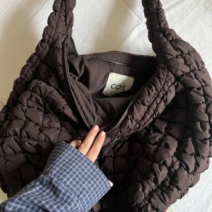 Väska cos  - Quiltad väska från cos i den stora modellen. Helt okej skick, lite lösa trådar. Svart/mörkbrun