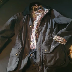 Barbour jacka med liberty innertyg - Fin och skön jacka, storlek 34 men passar bra på mig som har 36, väl omhändertagen, färgen är svår att få rättvis på bild men är åt de gråbruna hållet.