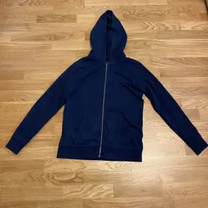 Säljer nu denna marin blåa zip hoddien från Jack and Jones. Tröjans storlek är 164 men jag som är 173 kan fortfarande använda den. Tröjan är sparsamt använd och skicket är 9/10. Hör av dig vid fler frågor. 