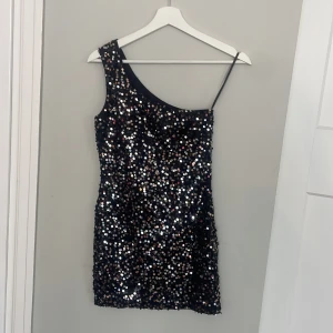 Paljettklänning enaxlad Forever 21 - Kort Paljettklänning med en Axel från Forever 21  Inköpt i USA för ett antal år sen och tyvärr för liten för mig nu Skulle även passa en XS skulle jag säga 
