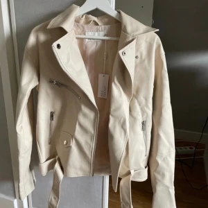 Skinnjacka  - Beige skinnjacka med detaljer, helt ny med lappen kvar.