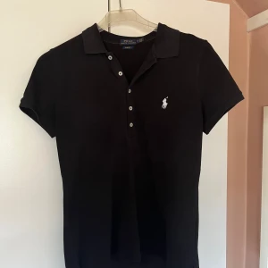 Ralph Lauren piké -  Svart piké från Ralph Lauren i storlek medium i fint skick men lite blekt vid kragen.