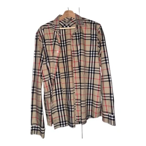 Burberry vintagerutig skjorta - Nu har vi fått in denna jättesnygga burberry skjortan!  Cond: 8/10 Strl: Medium (M) Defekter: saknar en mittenknapp på vänster handled men inget som påverkar varan synligt.  Fler bilder i detalj ges ut på begäran. 
