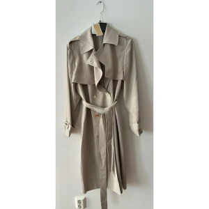 Michael Kors trenchcoat - Helt ny aldrig använd, tags kvar. Michael kors Drapy trenchcoat i färgen Dune.  Storlek XL. Köpt för 2595:- 
