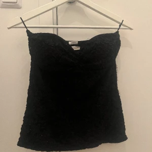 Svart bandeu topp med blommiga/spetsiga detaljer - Jättefin bandeu topp med blommiga detaljer på. Använd många gånger vilket syns men skulle absolut säga bra skick