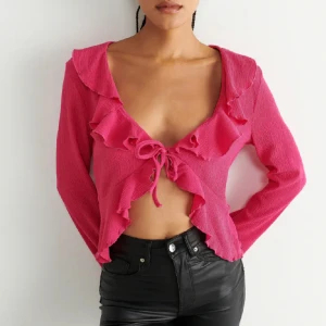 Rosa topp - Rosa långärmad topp med djup urringning och volanger nedtill och vid halsringningen. Storlek M. Oanvänd och har en i svart också. Kan sälja både svarta och rosa toppen för 350kr. Rosa: 200kr, pris kan diskuteras.