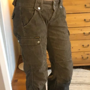 Y2k cargo pants - Ett par lågmidjade bruna cargobyxor med söta detaljer. Använda av mig 1 gång men känns som nyskick. Går ned till golvet på mig som är 178 och måtten är: midja 43cm, full längd 106 cm. Har snören vid fötterna så går att justera hur vida man vill ha de