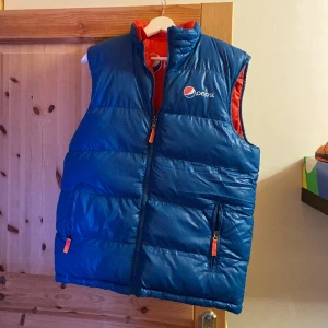 Pepsi Väst  - Pepsi Väst i storlek S (sitter som L). Västen är är i bra skick och nog aldrig använd. Går att vända den ut och in så att den blir röd istället (fickorna finns på den blåa sidan). 