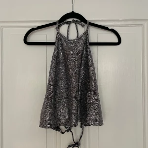 Glittertop - Glittrig top från monki med öppen rygg. Använd enbart ett fåtal gånger så den är i bra skick. Säljer på grund av att jag inte använder den längre. 