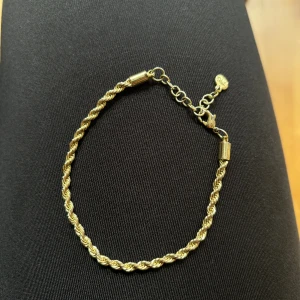 Armband  - Liknande kordel, går att ändra storlek på den med hjälp av hålen som finns. Ej äkta guld 