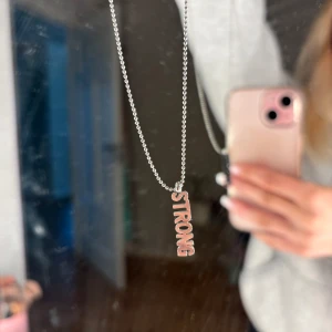 Halsband Ioaku - Silvrigt halsband ifrån Ioaku med texten Strong. Använder inte silver längre så kommer inte till användning.