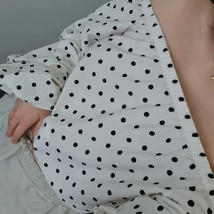 Vit off the shoulder topp - Säljer denna vita off the shoulder topp med svarta prickar. Toppen har en grej man kan knyta längst ner som man kan vika in eller ta bort. Använd två gånger och plagget har inga defekter