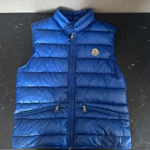 Moncler väst - Säljer denna sjukt feta mörk blåa moncler västen i storlek 1 / S. Skicket är 7/10. Inga hål eller liknande utan bara general wear. Alla zippers fungerar bra. Otroligt skön väst!