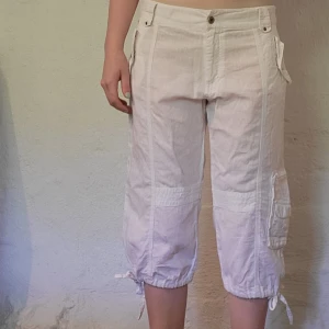 Vita lågmidjade capribyxor - Storlek 40. Bra skick förutom att de sytts ihop framtill, den sista bilden visar hur det ser ut. Jag skulle dock säga att det inte märks på avstånd. Byxkorna är lite genomskinliga.