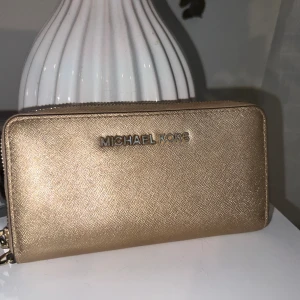 Michael kors plånbok guld - Säljer en snygg lite guld-glittrande plånbok ifrån Michael Kors. Inköpt på Raglady Väla Centrum.   Sparsamt använd.  Nypris runt 1300kr