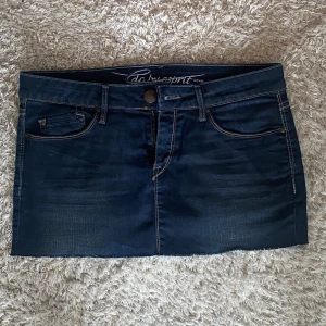 Lågmidjad jeanskjol - Säljer denna korta  jeanskjol, i mörkblå färg med mönster på fickorna.💕 Köpt begangnad, så ej omsydd av oss men ändå i fint skick!💕 Storlek 36/S. Skriv för mått, flera bilder och frågor! Köp via köp nu knappen!💕 Kolla gärna in våra andra annonser!