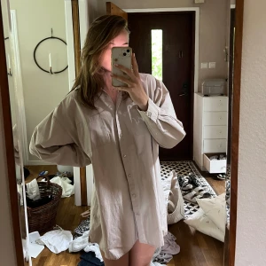 Beige skjortklänning  - En beige owersised skjorta som du kan ha som klänning eller som en owerisied skjorta. Använd fåtal gånger o väldigt fint skick. Skriv om du har vångar frågor💕
