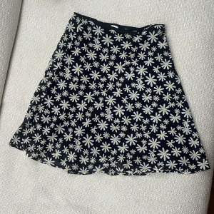 Blommig svart kjol  - Jag säljer min högmidjad blommig kjol som är i väldigt gott skick, endast använd 1 gång. 