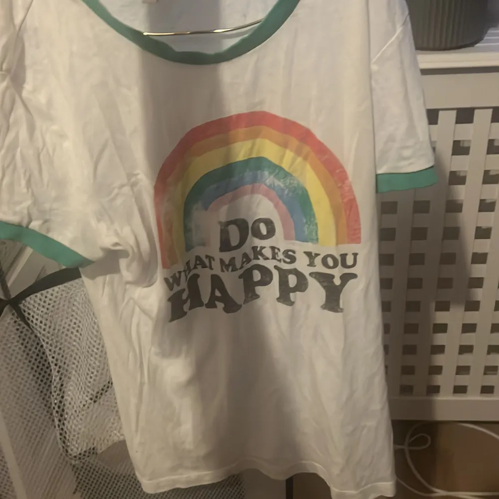 En sliten tröja med en regnbåge på och text där det står do What makes you happy , regnbågen är lite sliten men annars är den lite ut töjd . T-shirts.
