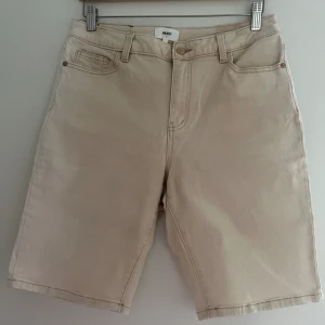 Jeansshorts, Object, L, beige - Beiga jeansshorts från Object i storlek L. Byxorna är i mycket god skick.   Material: 98% bomull, 2% elastan  Mått: Stuss/midja: ca 38 cm Ytterlängd ca 92 cm Innerlängd ca 25 cm  Plagget kommer från ett djur- och rökfritt hem. Plagget har inga skador