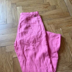 Rosa linnebyxor - rosa linnebyxor från Stockholm Lm.  Slitsar, väldigt lång modell. Smutsig i nedre kanten. Något noppig däruppe i bak. Sparsamt använda i övrigt