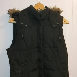 Puffer väst med pälsluva - Snygg svart zip up väst med en pälsluva Luvan sitter på med knappar så den går att ta av. Storlek är EUR 44, skulle säga att den passar som typ M. Allmänt bra skick, kom dm vid fler frågor💯