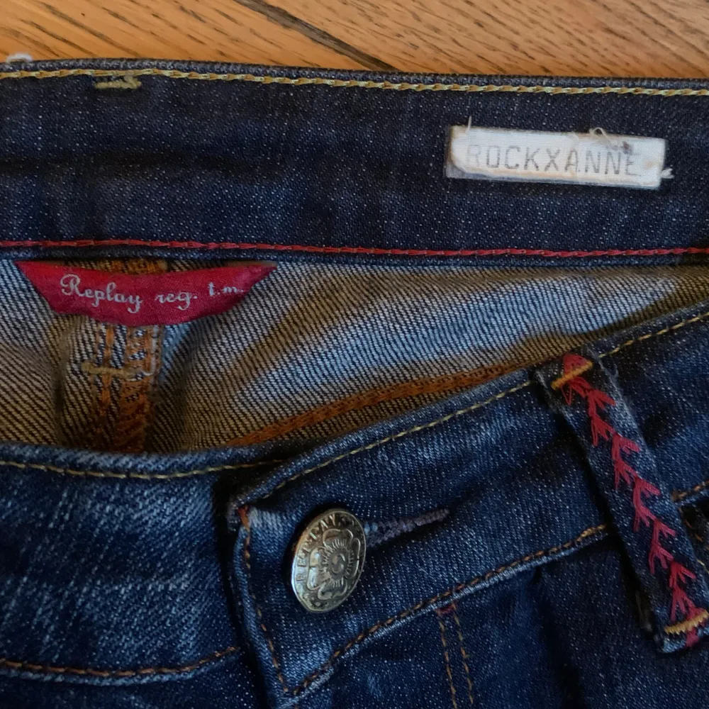 Mörkblå low waisted jeans med detaljer på bakfickan och röda detaljer vid midjan . Jeans & Byxor.