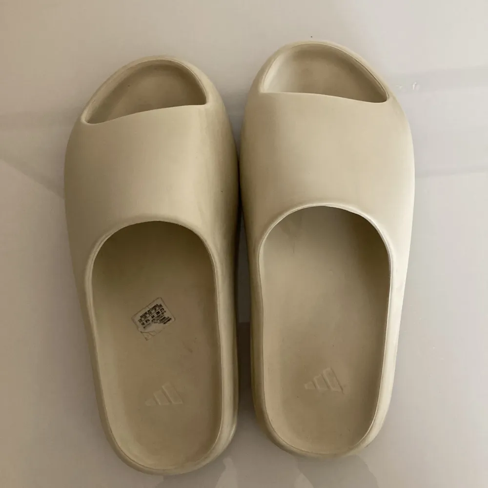 Adidas Yeezy Slides i strl 44 passar även 43. Sköna och stilrena tofflor perfekta till sommaren ☀️. Skick 7/10 lite creases men annars fina. Ingen skolåda därav priset. Hör av er vid minsta fundering, pris kan diskuteras! 🌻 / Mvh. Skor.