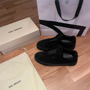 Axel Arigato Clean 360 Laceless  - Ett par väldigt fina Axel Arigato skor som knappt är använda, guldtexten på sidan är kvar på båda skorna och är i perfekt skick. Dom är väldigt försiktigt använda och väl omhändertagna som man ser på både undersidan av skon och mockan. Nypris: 2500 