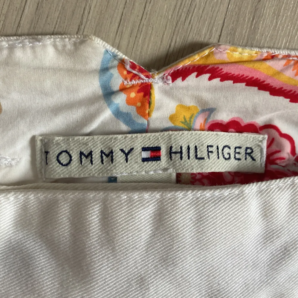 Super snygg vit Tommy Hilfiger jeans kjol med fina detaljer. Cool baksida och färgglada blommönster på insidan av kjolen. Säljs inte längre då det var en av deras limited edition kollektion. Använd 1 gång så Nyttskick!💝. Kjolar.