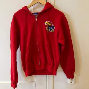 En röd Champion hoodie i storlek small, S. Kvaliten är bra.