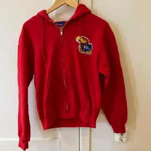 En röd Champion hoodie i storlek small, S. Kvaliten är bra.