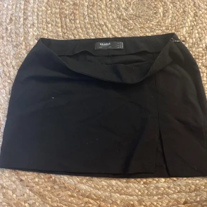 Mini kjol - En svart mini kjol med slits i storlek 38. Lågmidjade som sitter på höfterna. 