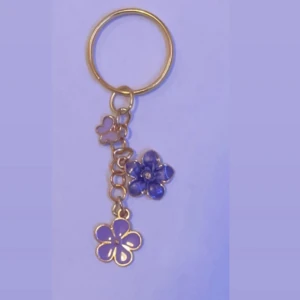 Nyckelring  - Guld nyckelring med blommor och fjärilar på som jag har tillverkat hemma. inga missfärgningar. Kostar 25kr.